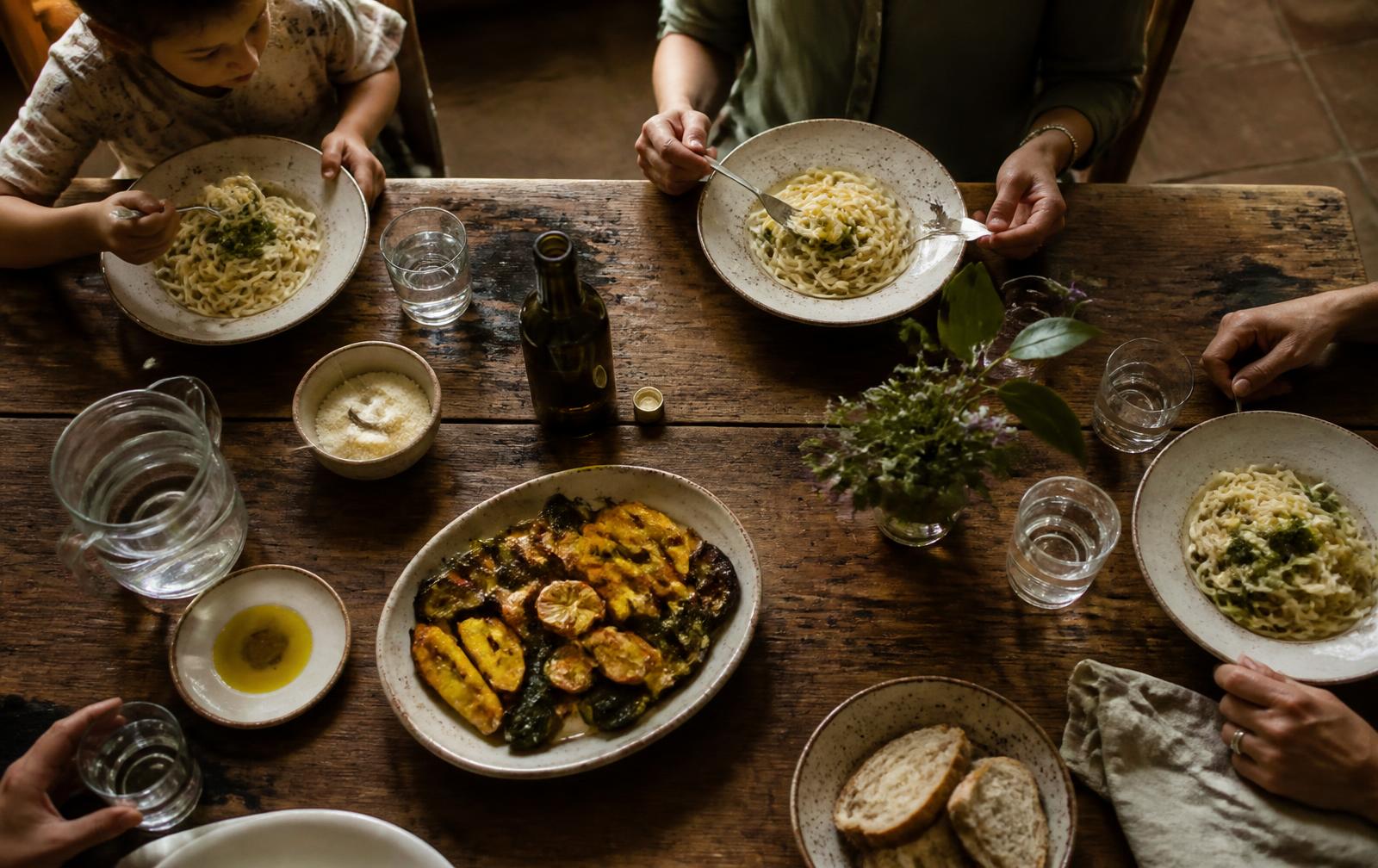 Warm Italian home dinner scene seen from above, shared plates on a wooden table